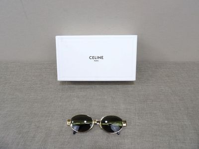 celine sunglasses in black and gold with a white box on a gray surface