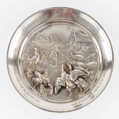 une image représentant une assiette en argent sur laquelle figurent une femme et des oiseaux