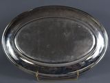 an oval silver plate with a stand on a grey background