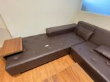 a brown leather couch with a wooden table on it