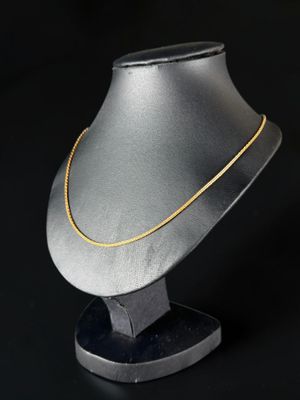 un collier en argent avec une chaîne en or sur fond noir