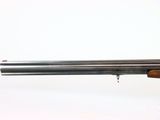 a close up of a gun with a wooden handle on a white background