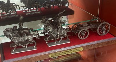 une vitrine remplie de figurines en argent représentant des chevaux et des calèches