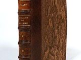 an old book with a leather cover sitting on top of a white surface