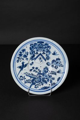 blue and white plate with flowers and birds on it on a black surface