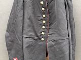 un vieux manteau militaire accroché à un mur, à côté d'un autre mur