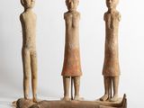 three figurines of three people standing on a piece of wood