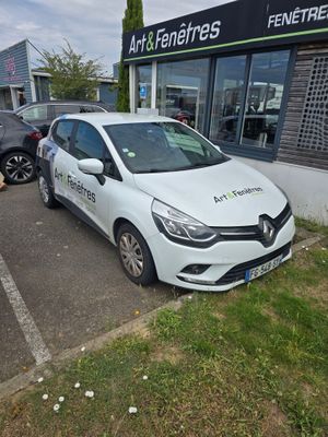 une voiture blanche garée dans un parking à côté d'un bâtiment