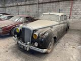 two old cars that are parked next to each other in a garage