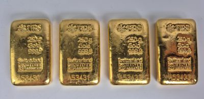 quatre lingots d'or sont disposés en rangée sur une surface blanche