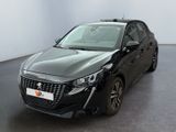 La voiture noire est garée dans une grande pièce aux murs blancs.