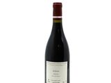 the bottle of red wine is sitting on a white surface