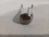 une cuillère en argent portant un monogramme, posée sur une surface blanche
