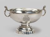 a silver bowl with a handle on a pedestal