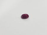 a single red ruby stone on a white surface