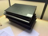 une pile de papiers posée sur un bureau, à côté d'un ordinateur portable