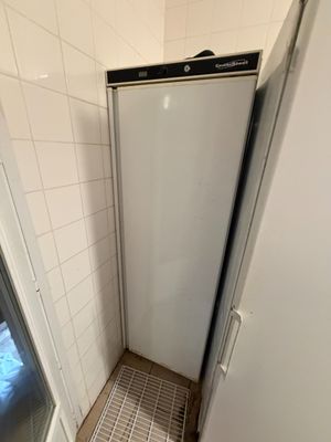 un grand réfrigérateur blanc dans un coin de la salle de bains