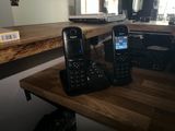 deux téléphones portables posés sur une table en bois à côté d'un ordinateur portable
