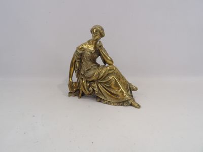 statue en or représentant une femme assise par terre, les mains posées sur les genoux