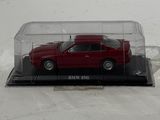 a red toy car in a clear case on a white surface