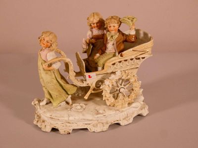 a figurine of two children riding in a horse drawn carriage
