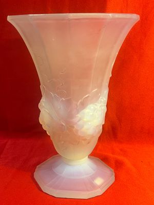 un vase en verre orné d'un visage, posé sur un tissu rouge