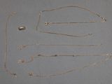 plusieurs types différents de colliers en or posés sur un fond gris