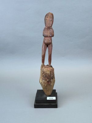 statue d'un homme debout sur un rocher, les mains dans les poches