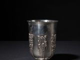 an old silver cup sitting on a table with a black background
