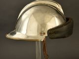 an old silver helmet with a leather band on a stand
