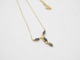 a gold necklace with black stones on a white background