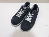 navy blue sued sneakers with white laces on a white surface
