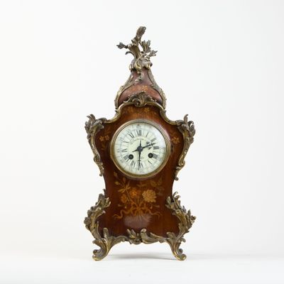 a clock that is sitting on a stand on a white surface