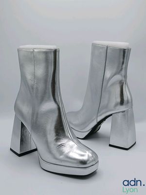 a pair of silver leather ankle boots on a white background