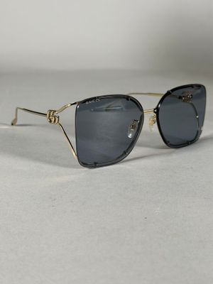 une paire de lunettes de soleil noires et dorées posées sur une surface blanche