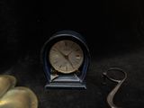 a small clock sitting on a table next to a pair of scissors