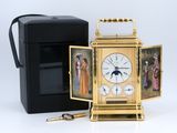 une horloge dorée ornée de motifs, à côté d'une boîte noire