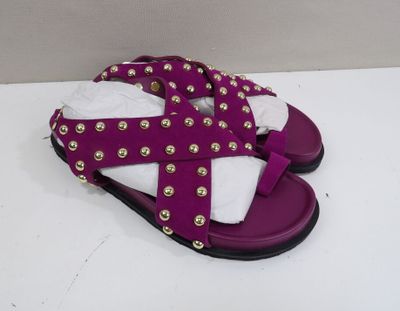 des sandales violettes et blanches ornées de clous dorés, posées sur une surface blanche