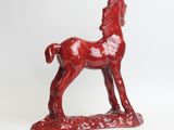 a red statue of a horse on a white surface