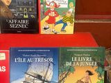 trois livres posés sur une table rouge