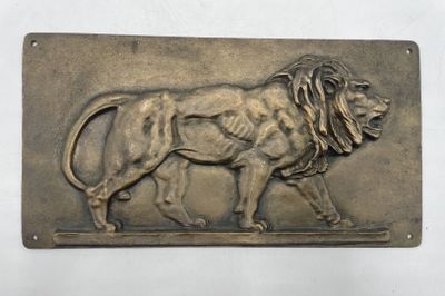 une plaque métallique sur laquelle est représenté un lion couché sur le flanc