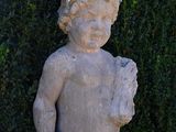 a small statue of a boy standing in front of a hedge