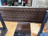 a booth with a bench and a table with a bottle of wine on it