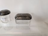 two glass containers on a clear shelf with a silver lid