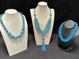 three necklaces with blue beads and a tassel on display