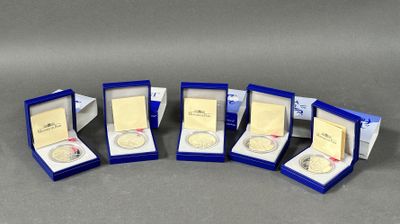 quatre médailles d'or dans une vitrine bleue posée sur un support gris