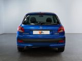 the back of a blue car is parked in a white room