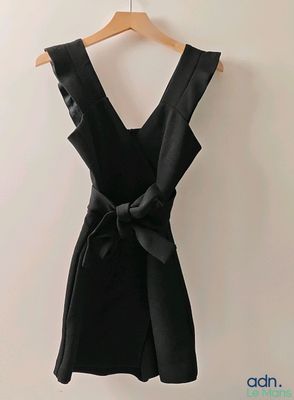 une robe noire suspendue à un cintre devant un mur blanc