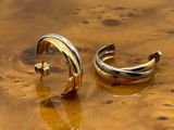 pair of gold and silver hoop earrings sitting on top of a wooden table
