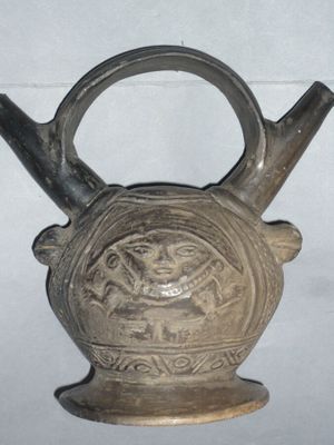 a small vase that has a handle on top of it